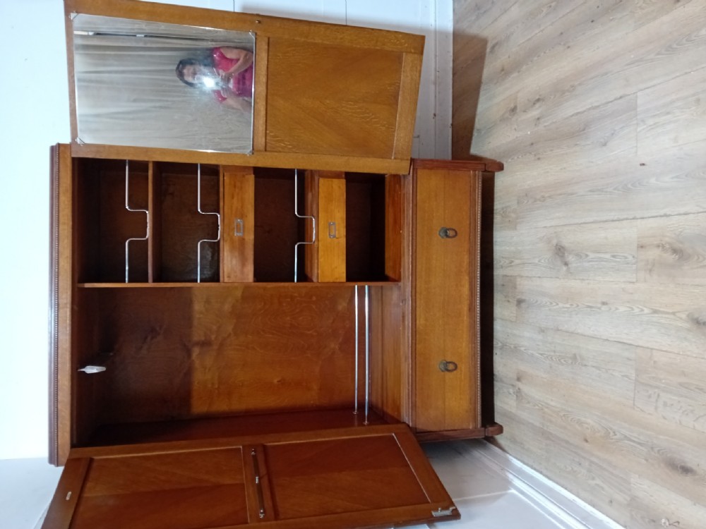 An Edwardian oak compactum wardrobe featuring two panelled doors with chevron oak veneers above a wide single drawer with brass drop handles. View II