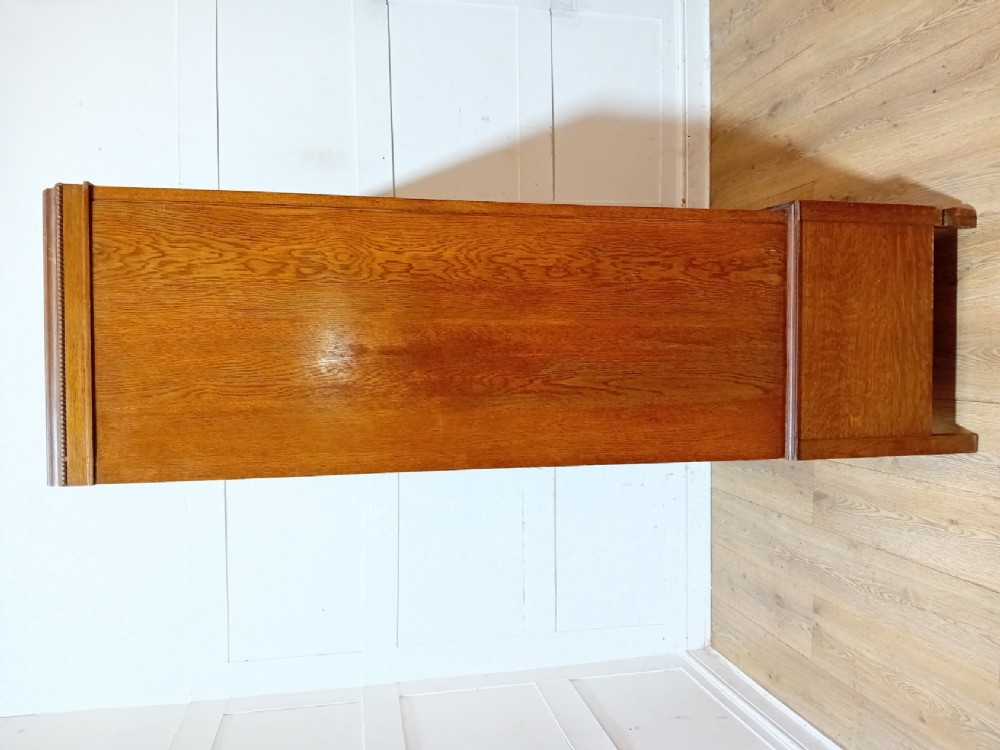 An Edwardian oak compactum wardrobe featuring two panelled doors with chevron oak veneers above a wide single drawer with brass drop handles. View IX