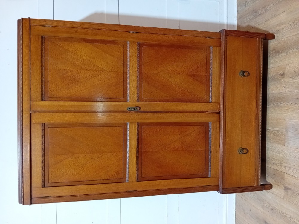 An Edwardian oak compactum wardrobe featuring two panelled doors with chevron oak veneers above a wide single drawer with brass drop handles. View XIV