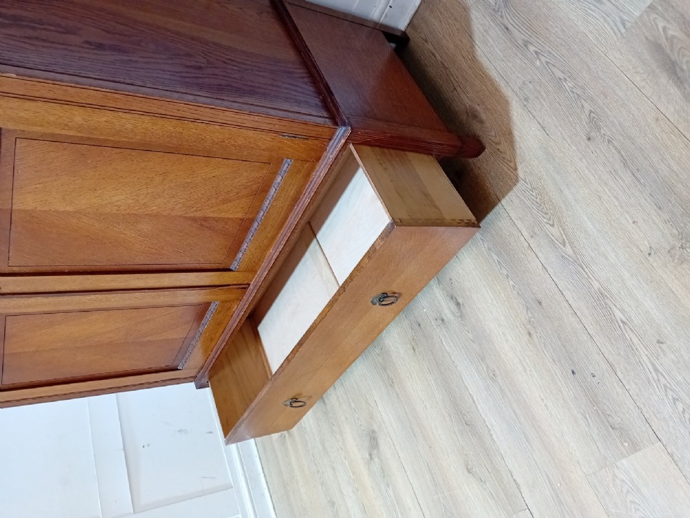 An Edwardian oak compactum wardrobe featuring two panelled doors with chevron oak veneers above a wide single drawer with brass drop handles. View XV