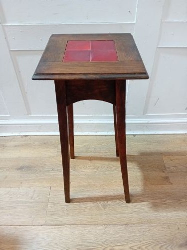 A tall Arts and Crafts dark oak jardiniere stand featuring four red ceramic tiles inset on the top surface and slim tapered legs. View X