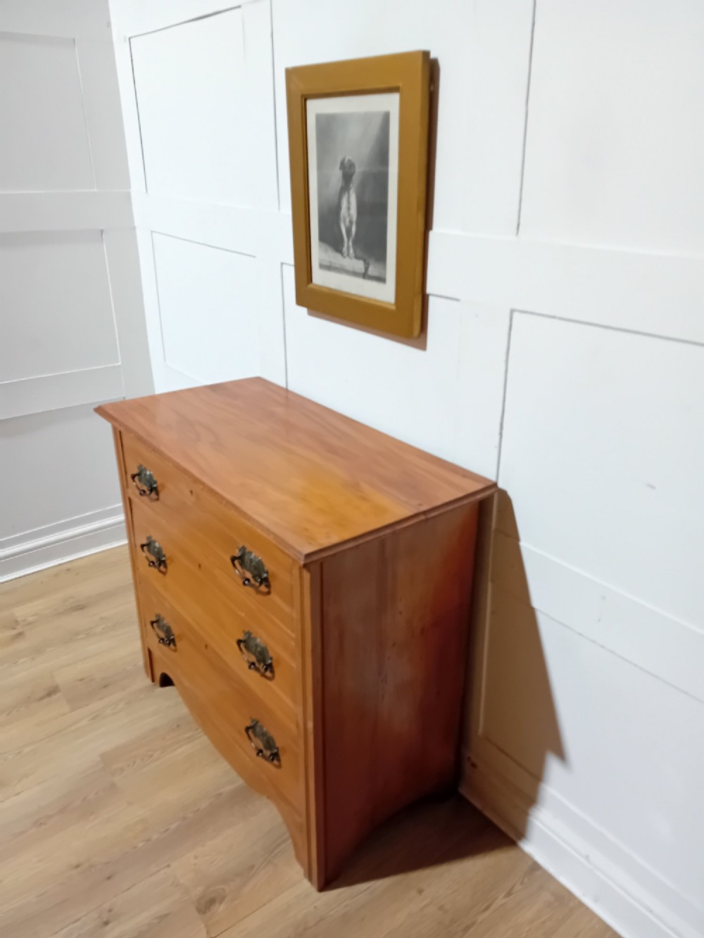 A late nineteenth-century satinwood chest of drawers with three full-width drawers and dark metal drop handles.