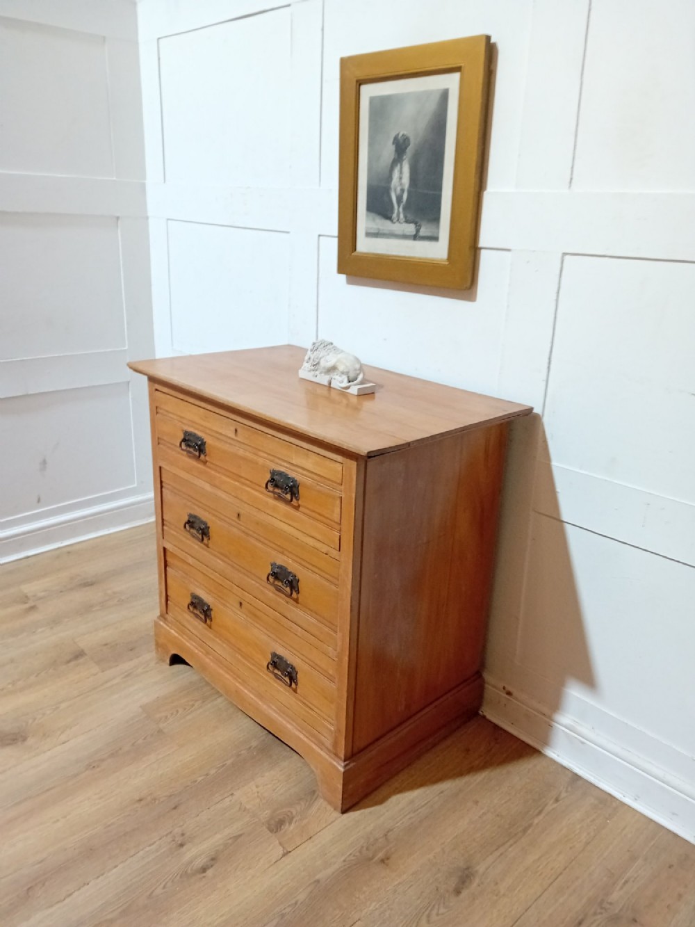 A late nineteenth-century satinwood chest of drawers with three full-width drawers and dark metal drop handles. View III