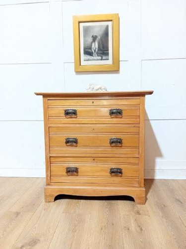 A late nineteenth-century satinwood chest of drawers with three full-width drawers and dark metal drop handles. View V