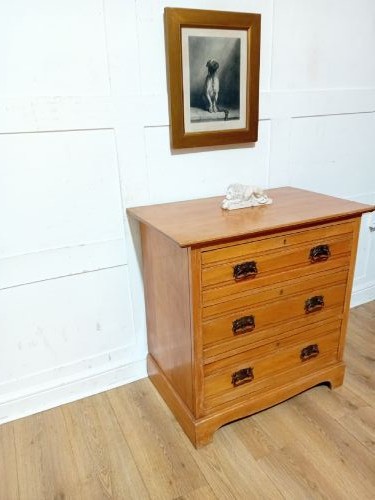 A late nineteenth-century satinwood chest of drawers with three full-width drawers and dark metal drop handles. View VI