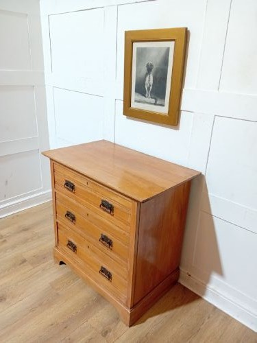 A late nineteenth-century satinwood chest of drawers with three full-width drawers and dark metal drop handles. View VIII