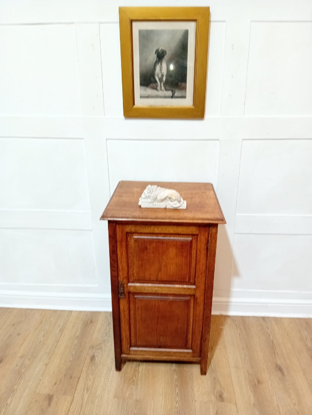 A warm brown Arts and Crafts oak hall cupboard with a two-panel door and a moulded flat top. View X
