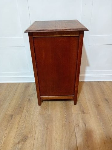 A warm brown Arts and Crafts oak hall cupboard with a two-panel door and a moulded flat top. View VI