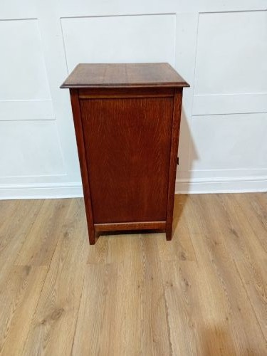 A warm brown Arts and Crafts oak hall cupboard with a two-panel door and a moulded flat top. View VIII