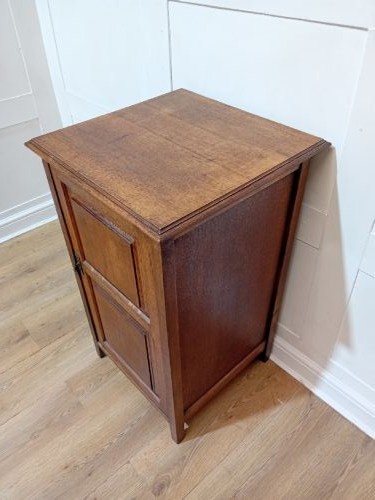 A warm brown Arts and Crafts oak hall cupboard with a two-panel door and a moulded flat top. View XII