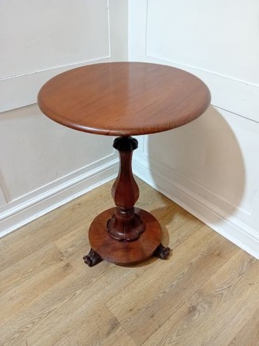 A late Victorian circular mahogany side table featuring a smooth turned pedestal column and a shaped base. View X