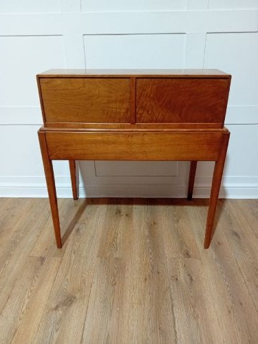 An Arts and Crafts Cotswold School wooden writing bureau featuring a fall-front upper section, two lower drawers with turned wooden knobs, and slender tapered legs. View XI