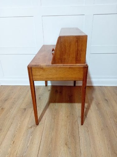 An Arts and Crafts Cotswold School wooden writing bureau featuring a fall-front upper section, two lower drawers with turned wooden knobs, and slender tapered legs. View X