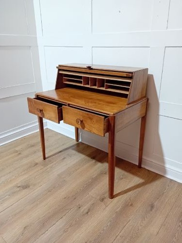 An Arts and Crafts Cotswold School wooden writing bureau featuring a fall-front upper section, two lower drawers with turned wooden knobs, and slender tapered legs. View VIII
