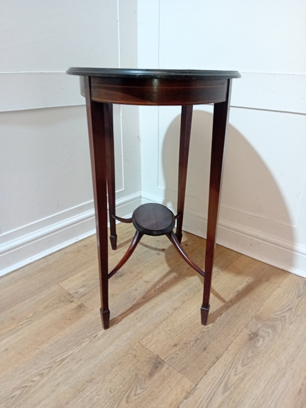 An antique oval dark mahogany occasional table featuring slender tapered legs connected by curved stretchers with a small central circular shelf. View III