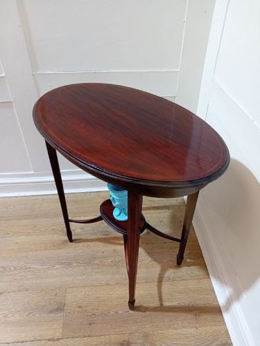 An antique oval dark mahogany occasional table featuring slender tapered legs connected by curved stretchers with a small central circular shelf. View XIII