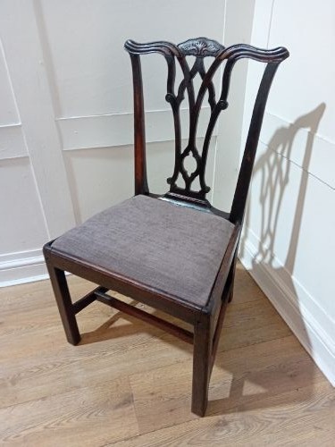 An 18th-century George III mahogany side chair featuring a carved pierced splat back, upholstered drop-in seat, and straight square legs with H-stretcher support.