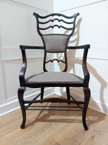 An antique dark mahogany Edwardian armchair featuring a contoured ladder back rest, padded central panel, curved armrests, and grey upholstered seat. View VII