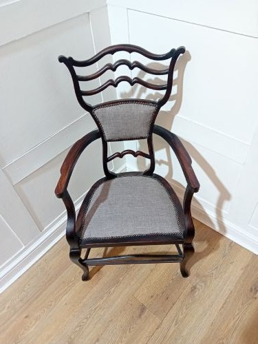 An antique dark mahogany Edwardian armchair featuring a contoured ladder back rest, padded central panel, curved armrests, and grey upholstered seat. View XIV
