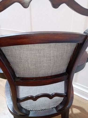 An antique dark mahogany Edwardian armchair featuring a contoured ladder back rest, padded central panel, curved armrests, and grey upholstered seat. View XIII