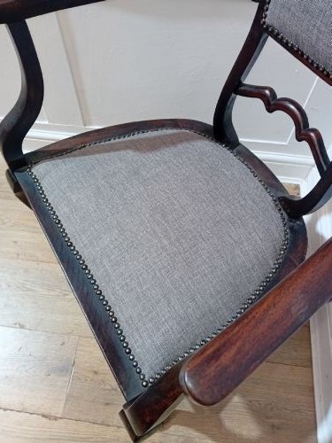 An antique dark mahogany Edwardian armchair featuring a contoured ladder back rest, padded central panel, curved armrests, and grey upholstered seat. View XI