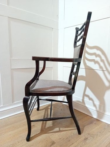 An antique dark mahogany Edwardian armchair featuring a contoured ladder back rest, padded central panel, curved armrests, and grey upholstered seat. View VIII
