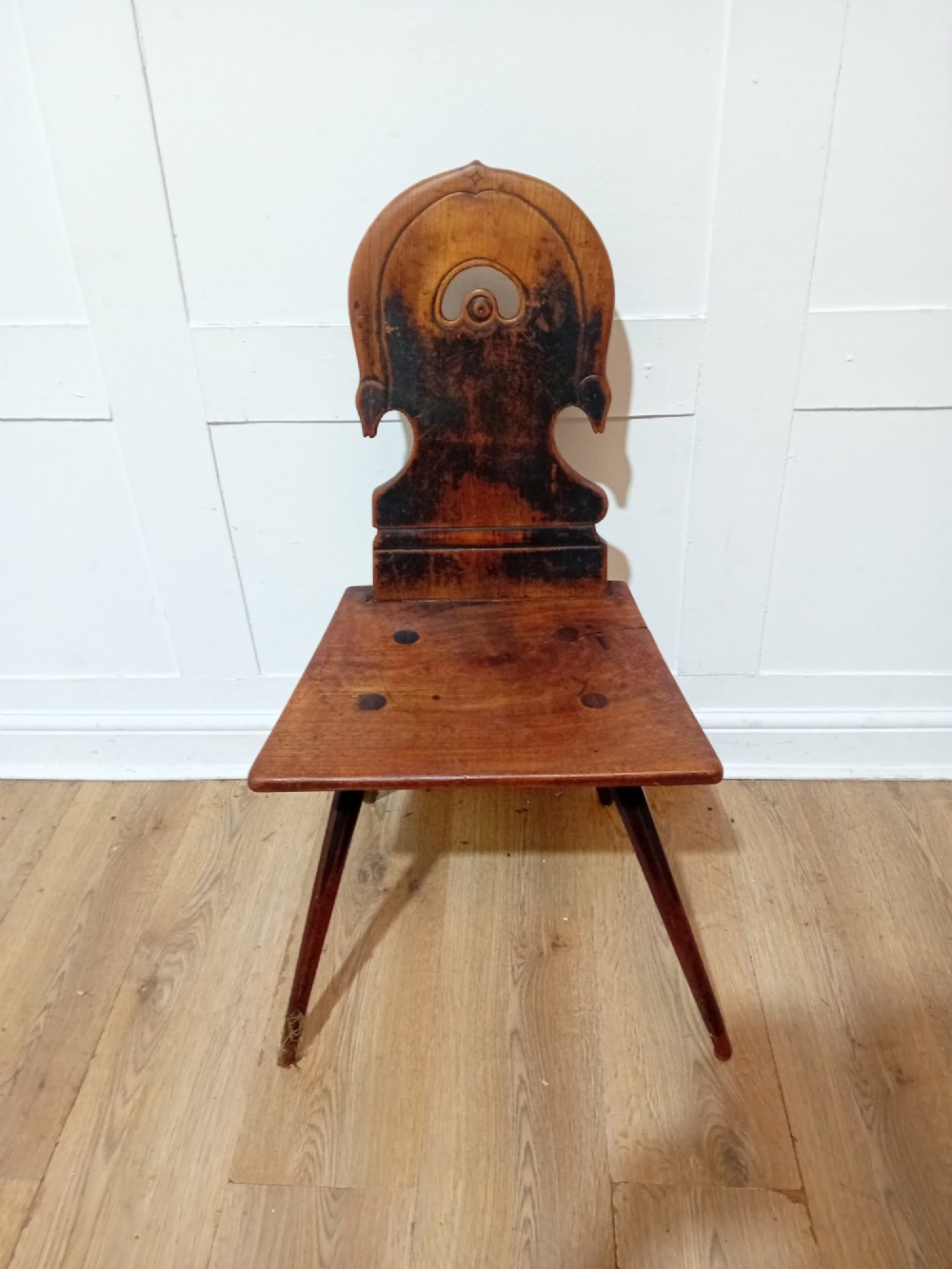 An antique Bavarian folk art wooden side chair featuring a carved cartouche backrest with a central cutout, a slab seat with visible joinery, and splayed legs. View III