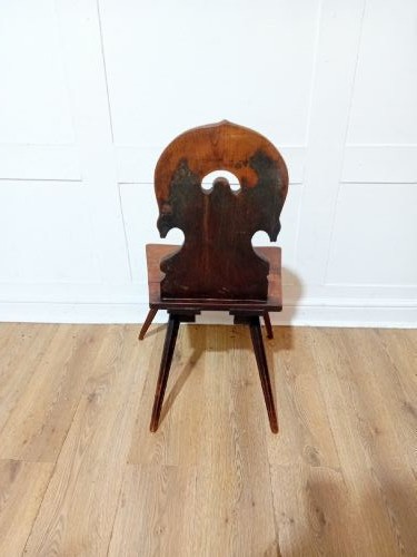 An antique Bavarian folk art wooden side chair featuring a carved cartouche backrest with a central cutout, a slab seat with visible joinery, and splayed legs. View VII