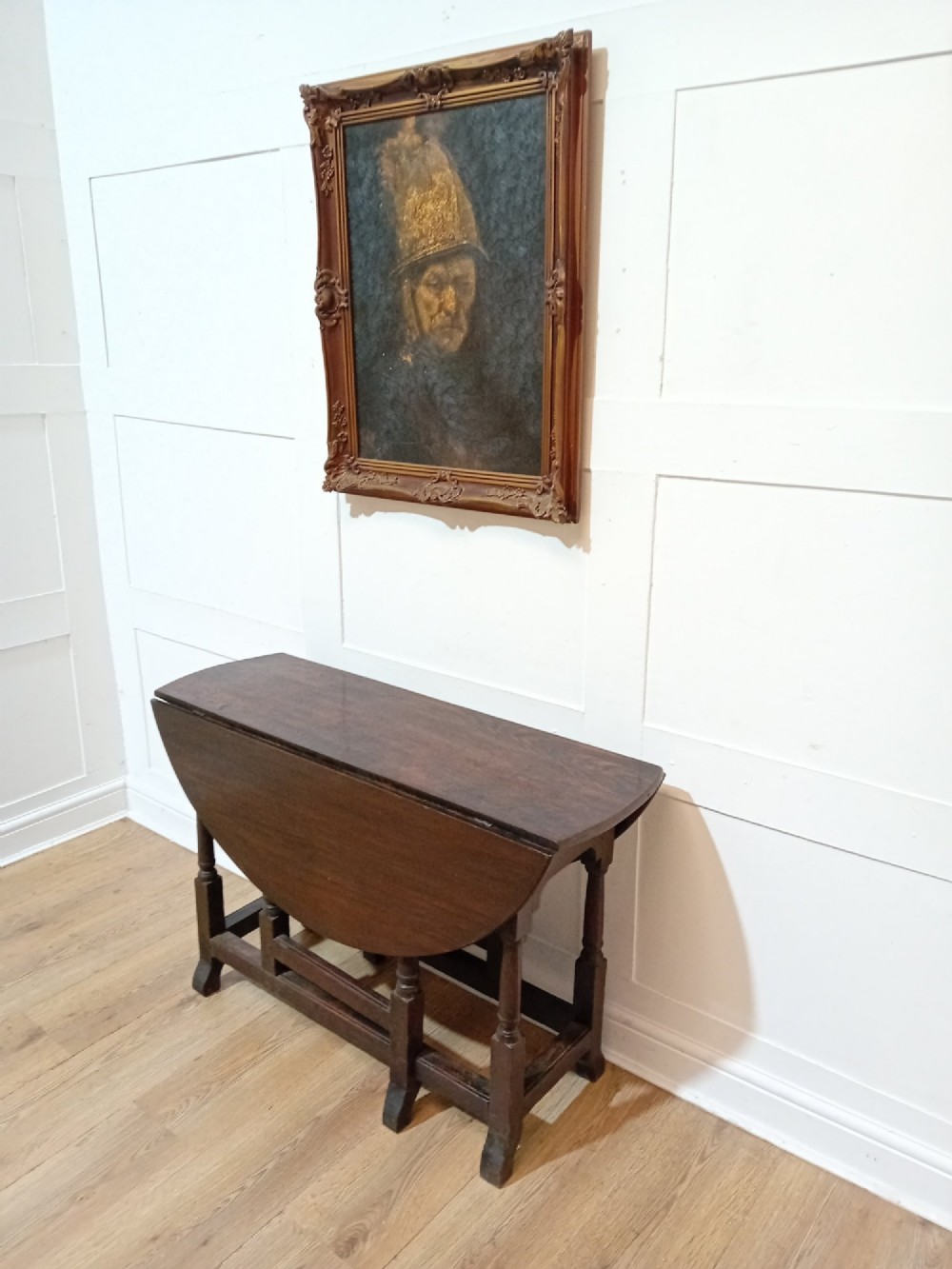 A seventeenth-century dark oak gateleg table with folded leaves, turned legs, and a stretcher base.