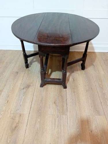 A seventeenth-century dark oak gateleg table with folded leaves, turned legs, and a stretcher base. View XI