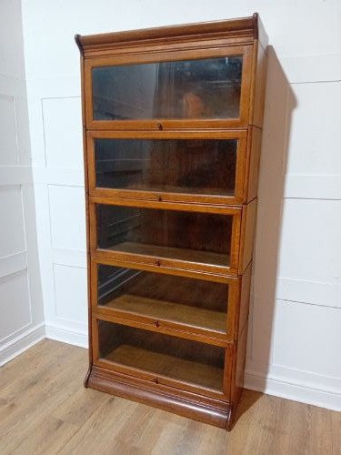 An Edwardian golden oak five-tier sectional barrister bookcase featuring glazed lifting doors with brass handles and a moulded top cornice. View III