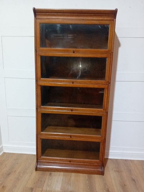 An Edwardian golden oak five-tier sectional barrister bookcase featuring glazed lifting doors with brass handles and a moulded top cornice. View IV