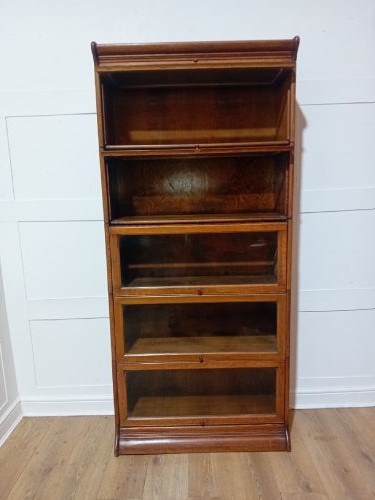 An Edwardian golden oak five-tier sectional barrister bookcase featuring glazed lifting doors with brass handles and a moulded top cornice. View VIII