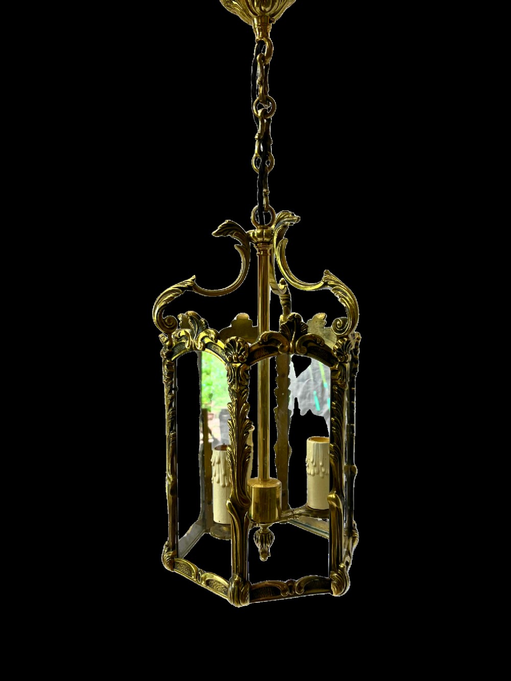 An ornate French style brass hanging hall lantern featuring glazed panels, acanthus scroll details, and three interior faux candle light sockets. View II