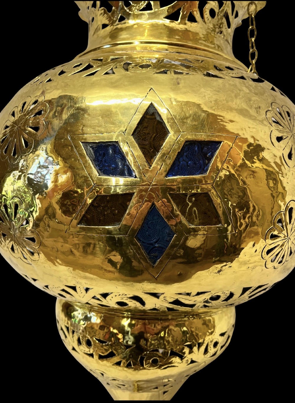 A pierced brass hanging lantern featuring floral and geometric fretwork, blue glass inserts, a flared scalloped rim, and a pointed base finial. View II