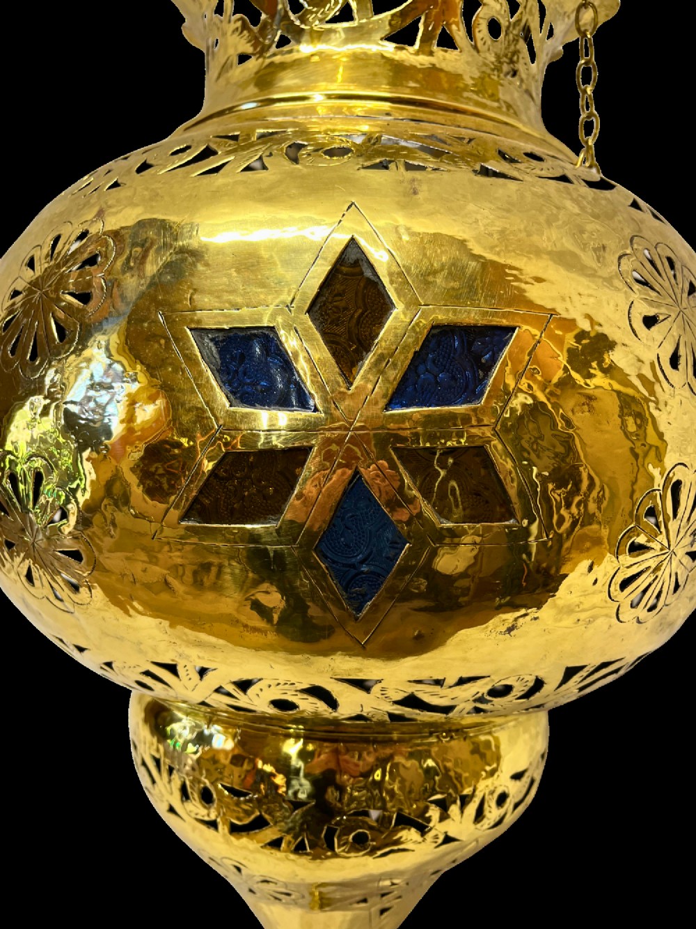 A pierced brass hanging lantern featuring floral and geometric fretwork, blue glass inserts, a flared scalloped rim, and a pointed base finial. View IV
