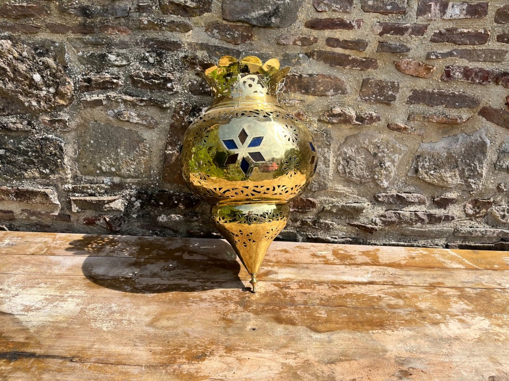 A pierced brass hanging lantern featuring floral and geometric fretwork, blue glass inserts, a flared scalloped rim, and a pointed base finial. View V