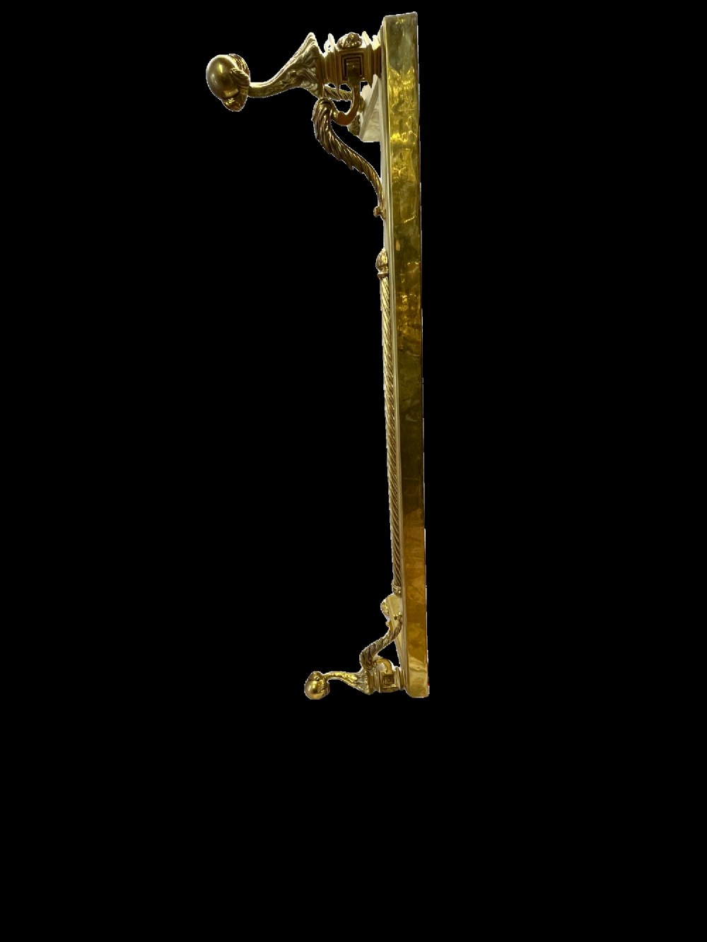 An Edwardian polished brass fireplace fender with decorative end finials and a low moulded base. View III