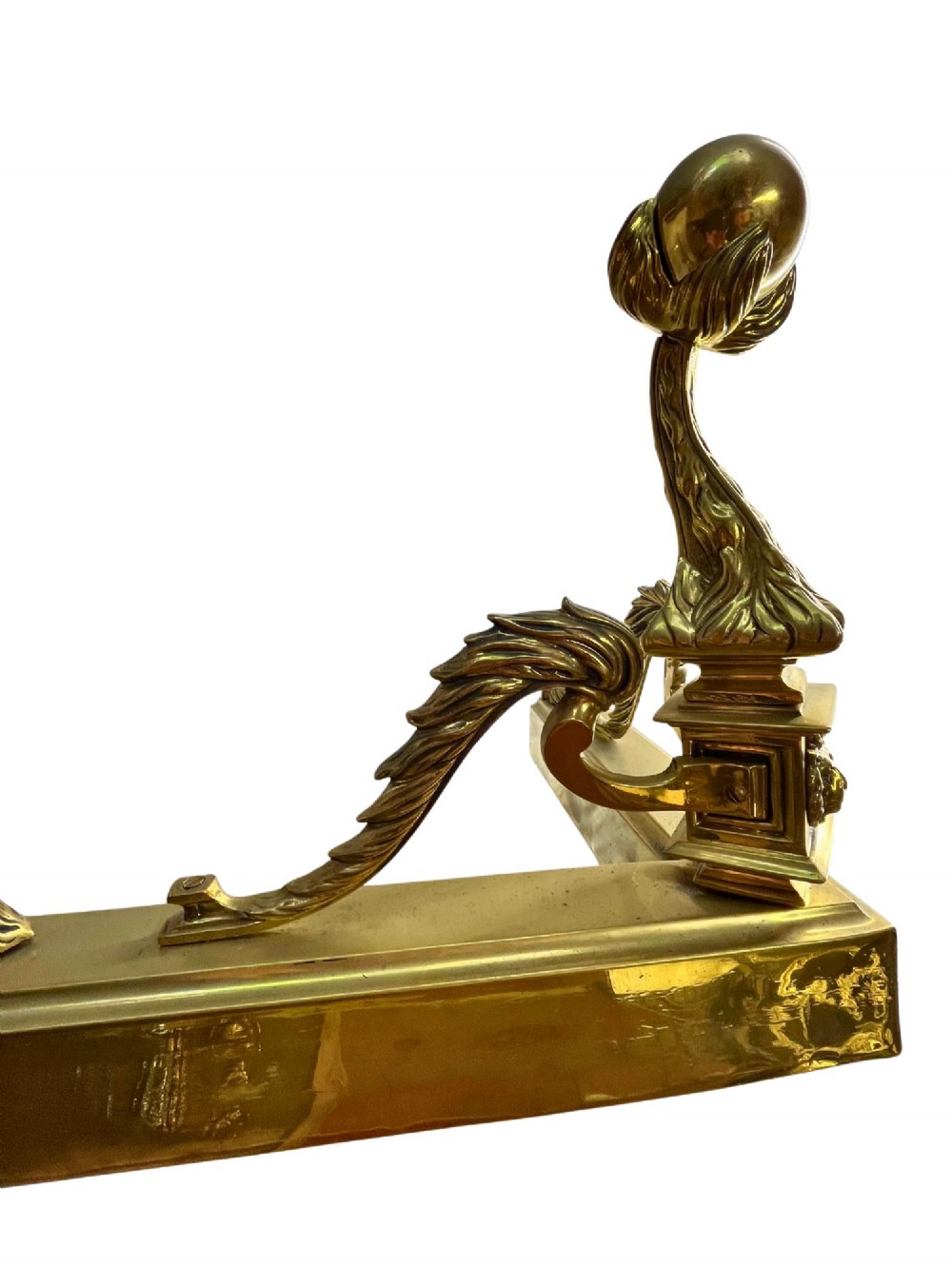 An Edwardian polished brass fireplace fender with decorative end finials and a low moulded base. View IV