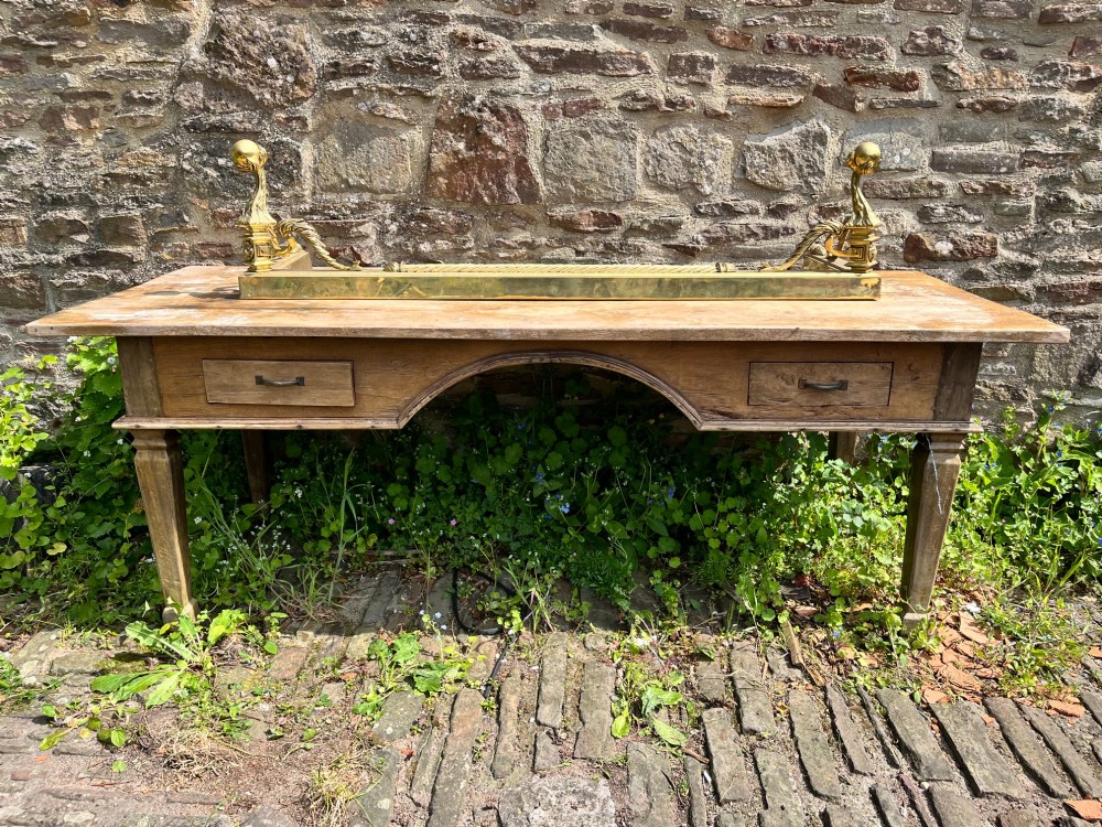 An Edwardian polished brass fireplace fender with decorative end finials and a low moulded base. View VI