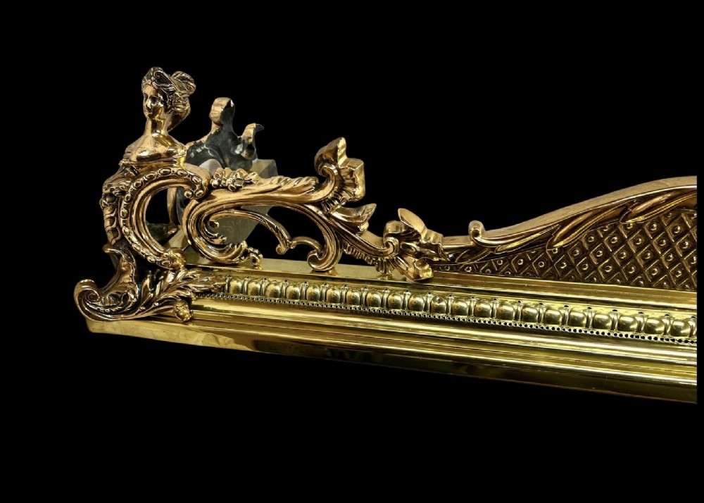 An ornate brass and bronze fireplace fender featuring Rococo scrollwork, lattice panels, and female figural end ornaments. View II