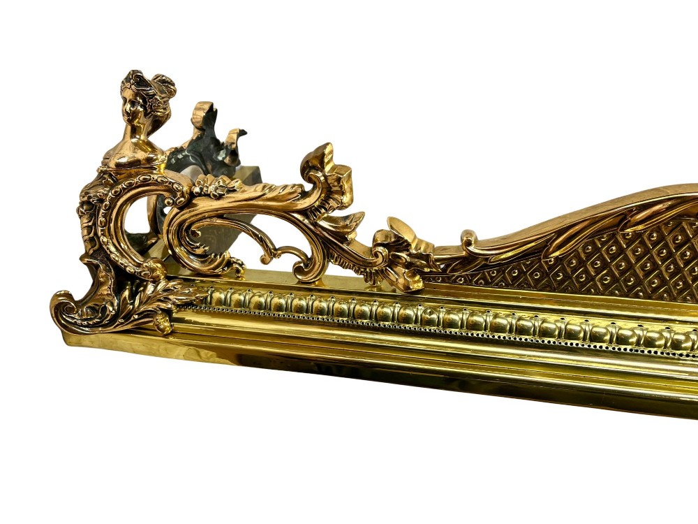 An ornate brass and bronze fireplace fender featuring Rococo scrollwork, lattice panels, and female figural end ornaments. View V