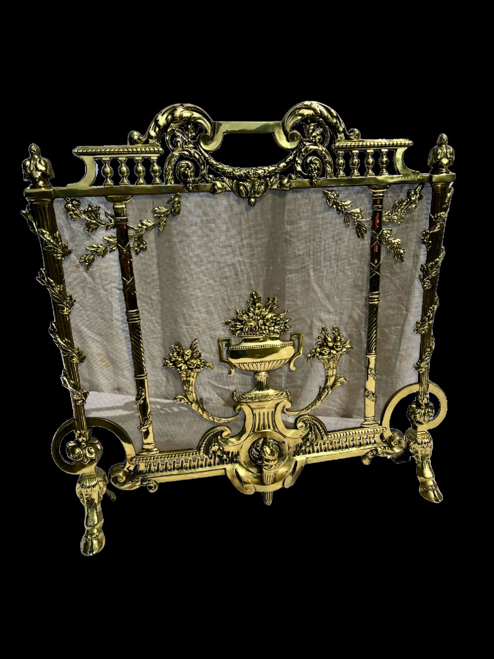 A cast brass fire screen featuring ornate scrollwork, a central urn motif, floral swags, and a mesh background panel. View II