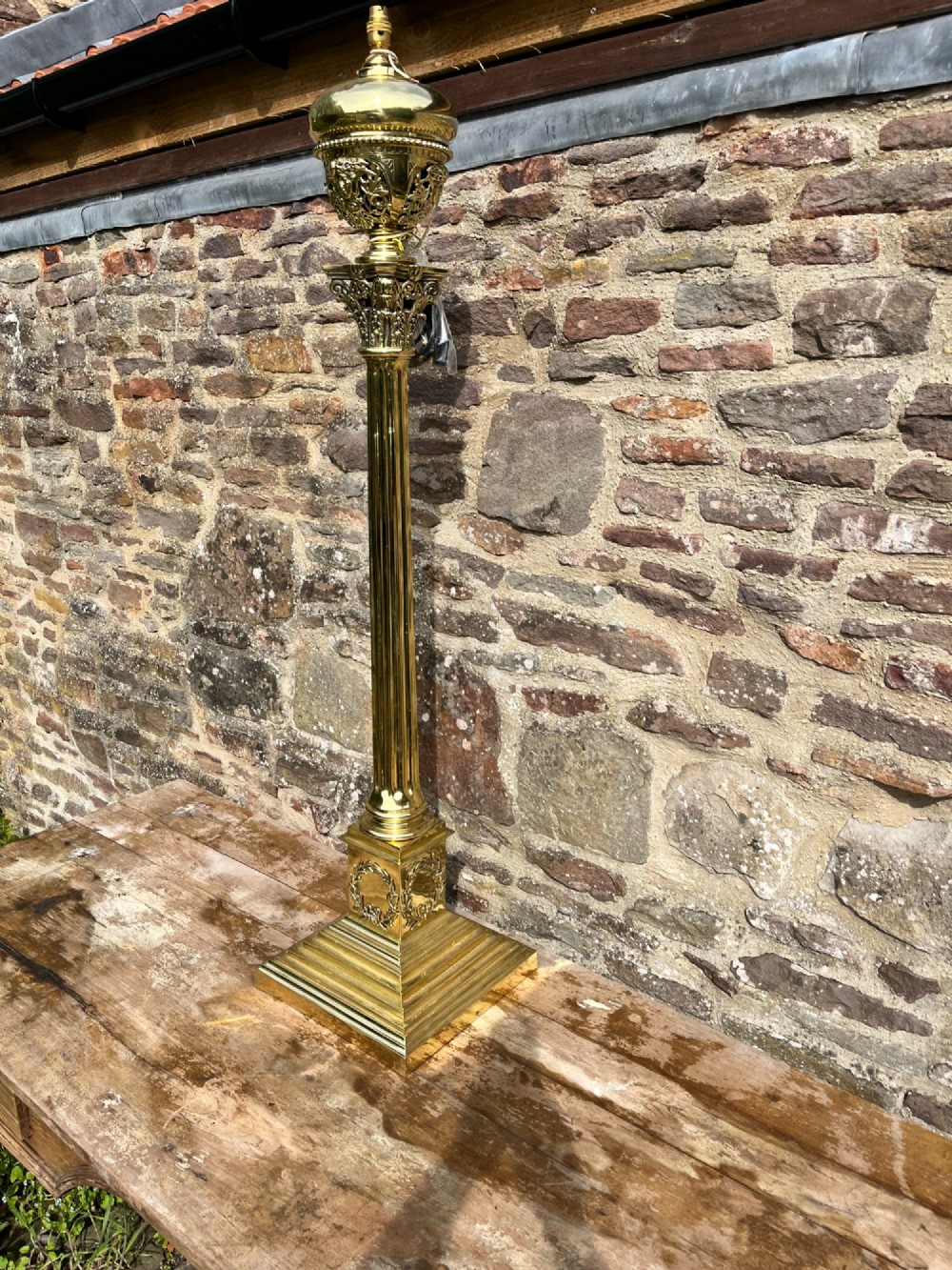 An antique polished brass standard floor lamp featuring a fluted column, classical Corinthian capital, urn motif, and stepped square base. View IV