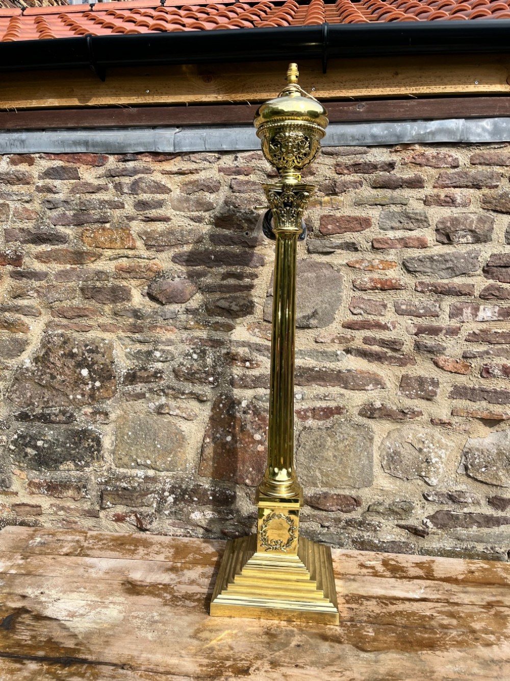 An antique polished brass standard floor lamp featuring a fluted column, classical Corinthian capital, urn motif, and stepped square base. View V