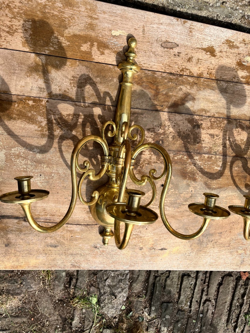 A pair of brass candle wall sconces featuring multi-branch scrolling arms, candle cups with drip pans, and turned central spindles. View III