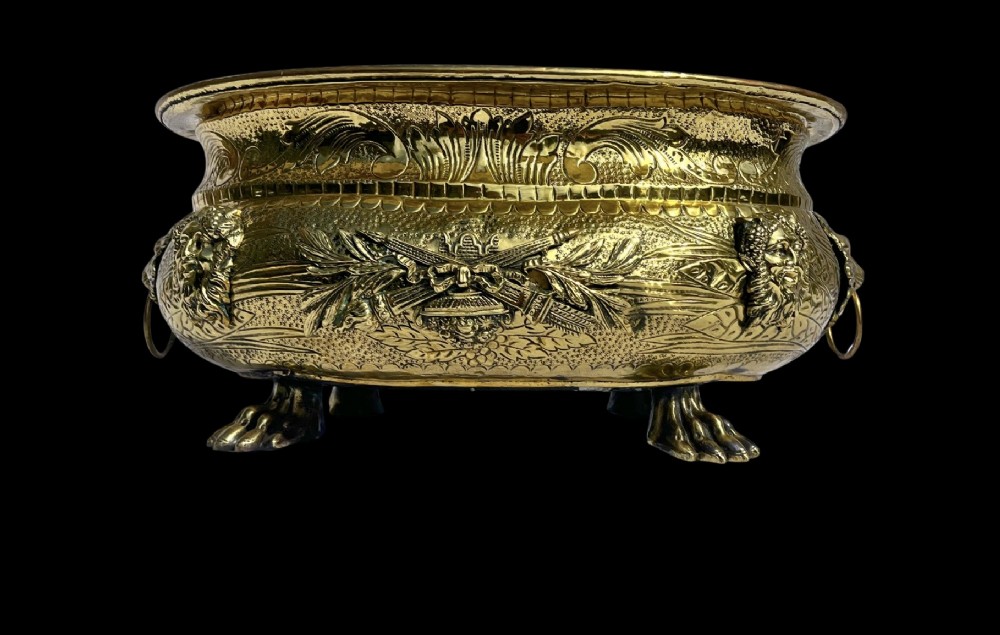 An embossed brass French jardiniere featuring side drop handles and lion mask details supported on claw feet. View II