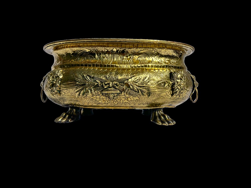 An embossed brass French jardiniere featuring side drop handles and lion mask details supported on claw feet. View III