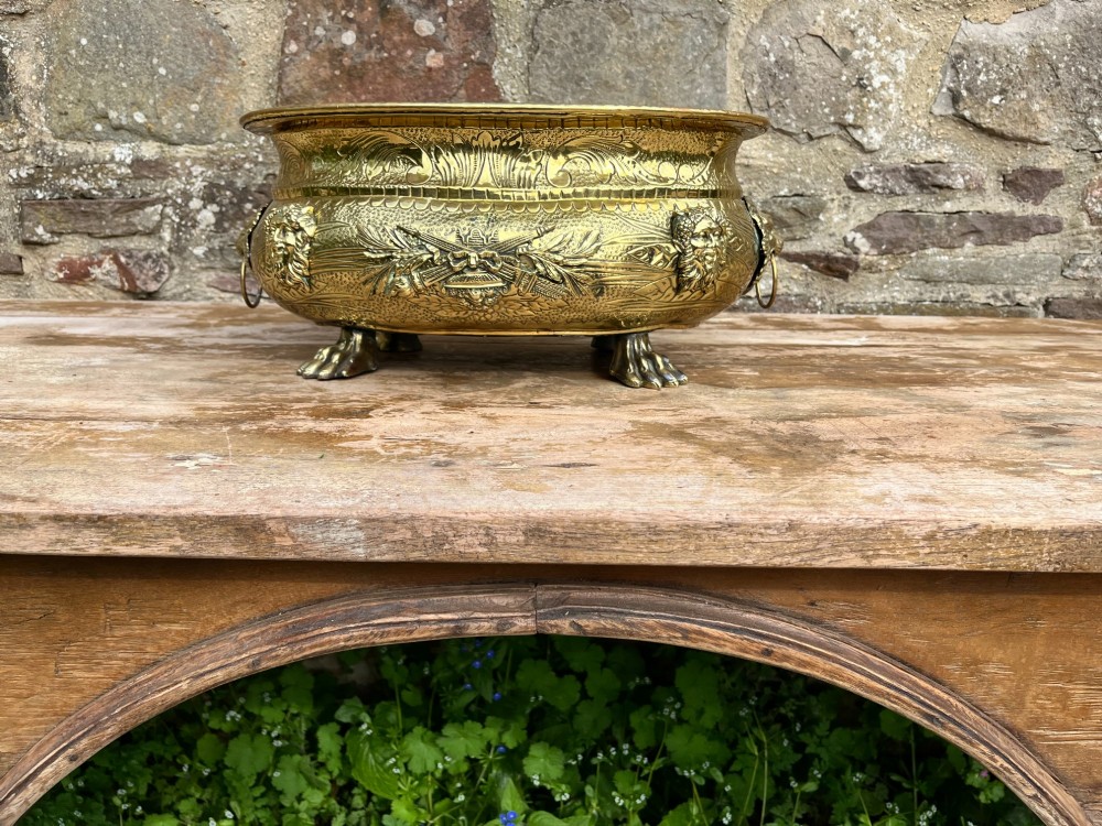 An embossed brass French jardiniere featuring side drop handles and lion mask details supported on claw feet. View IV
