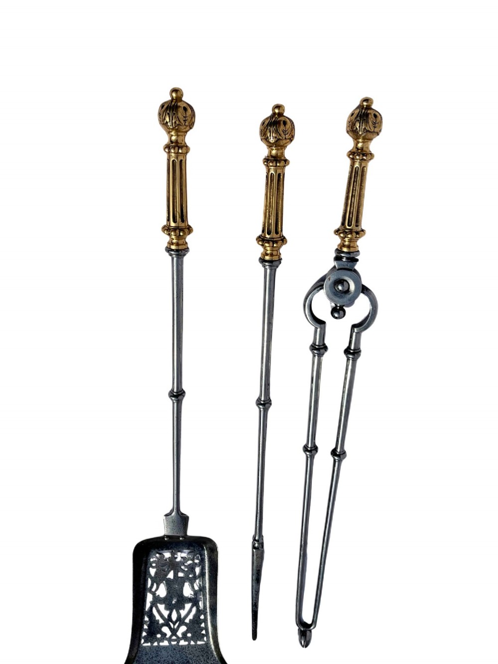 A three-piece set of antique fire tools including a shovel, poker, and tongs with brass handles and steel shafts.
